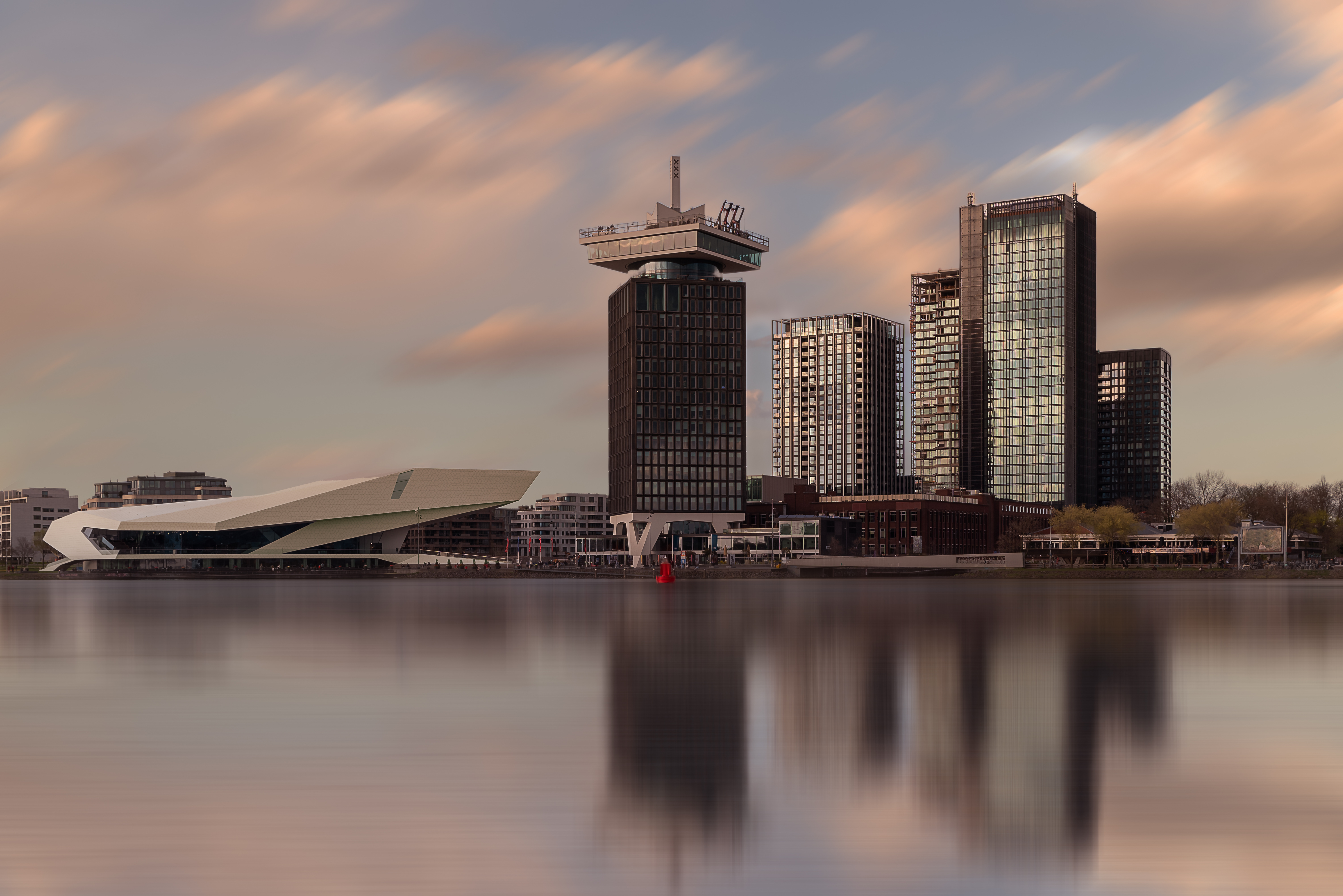 Eye Filmmuseum and the A'DAM Tower facing the city across the IJ Panoramic landscape about the Amsterdam's skylines included the A'dam lookout tower and Eye Film Museum too. the buildings are reflected on the water.