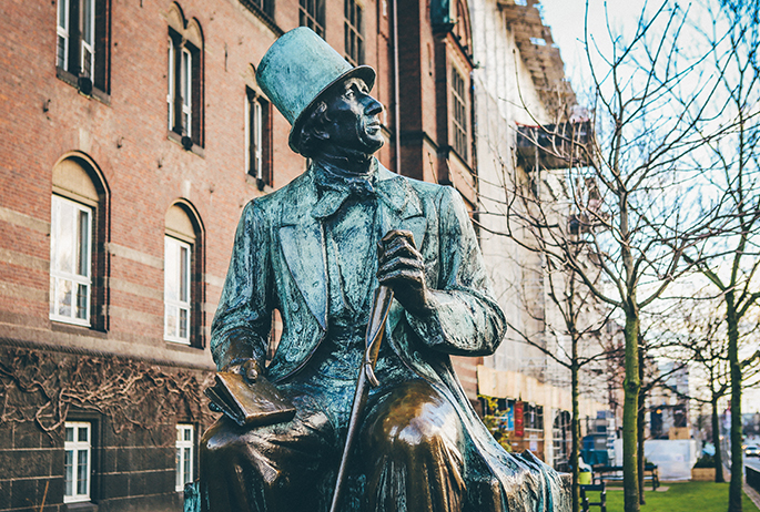 At Copenhagen City Hall Square, facing H.C. Andersens Boulevard features a statue of Hans Christian Andersen who sits with a book.